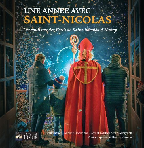 Une photographie avec Saint Nicolas au centre de dos avec deux adultes et un enfant. Ils sont situé à la fenêtre de l'hôtel de ville de Nancy devant la place Stanislas