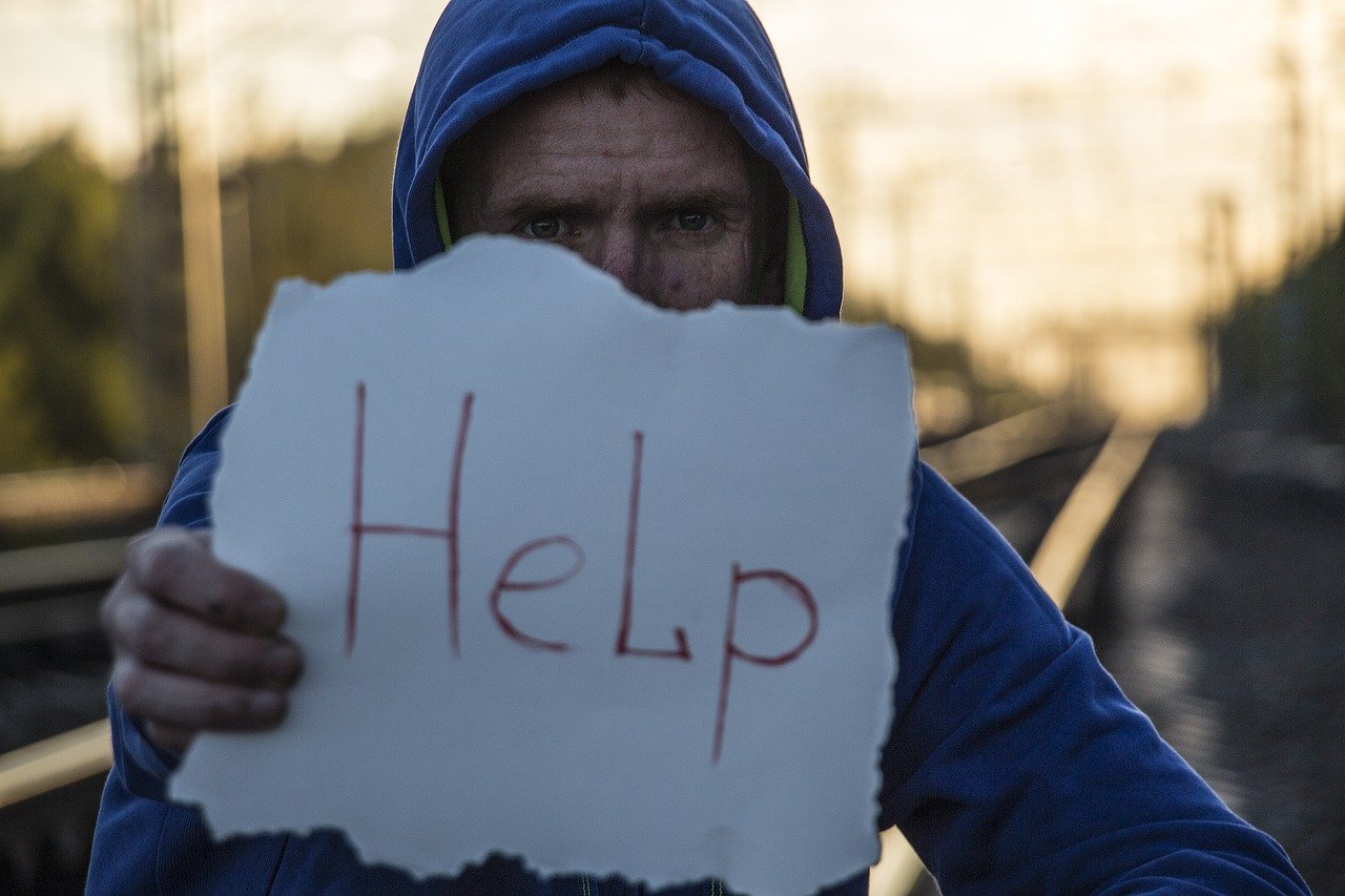 Homme tenant une pancarte noté "Help"